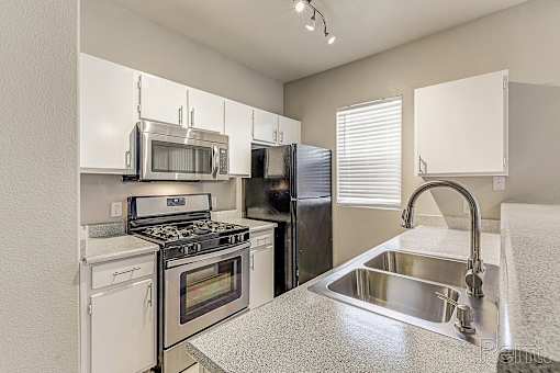 A kitchen with a stove, oven, refrigerator, and microwave.