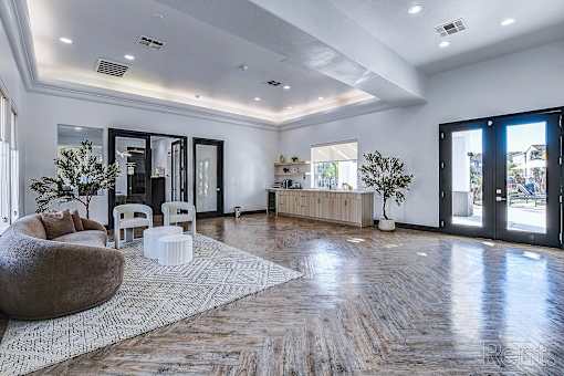 A spacious living room with a brown armchair, a white side table, and a large rug.