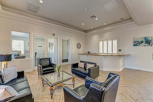 A living room with a glass table and leather chairs.