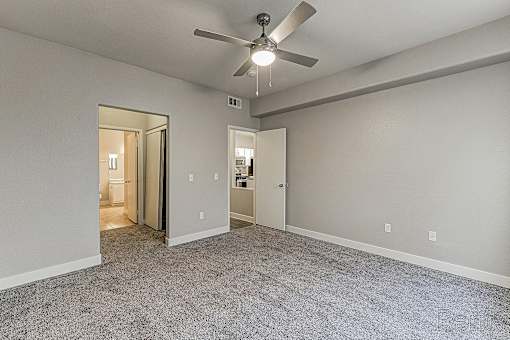 A room with a ceiling fan and carpeted floor.
