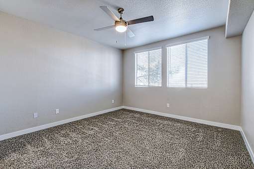 A room with a ceiling fan and carpeted floor.