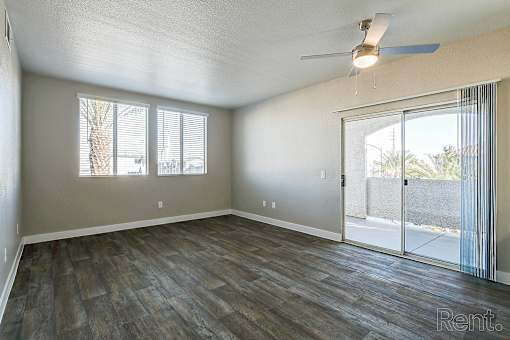 A room with a ceiling fan and sliding glass doors.
