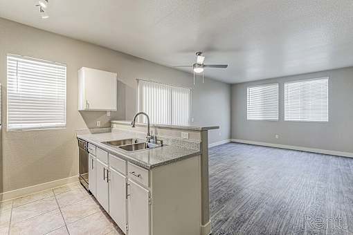 A kitchen with a sink, cabinets, and a ceiling fan.