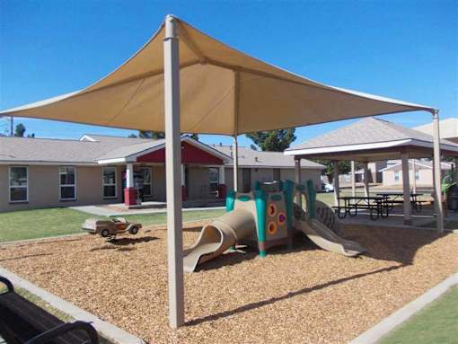 A playground with a yellow canopy and a slide.
