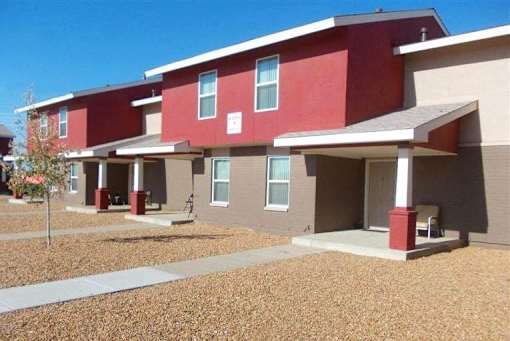A red and beige building with a tree in front.