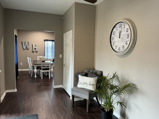 a living room with a large clock on the wall and a chair