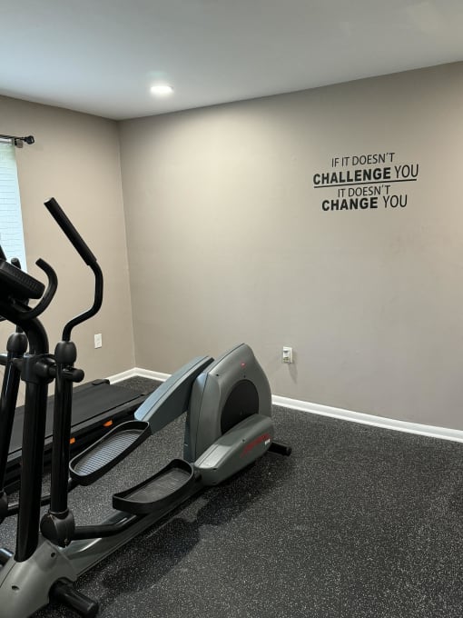 a gym with treadmills and a motivation quote on the wall