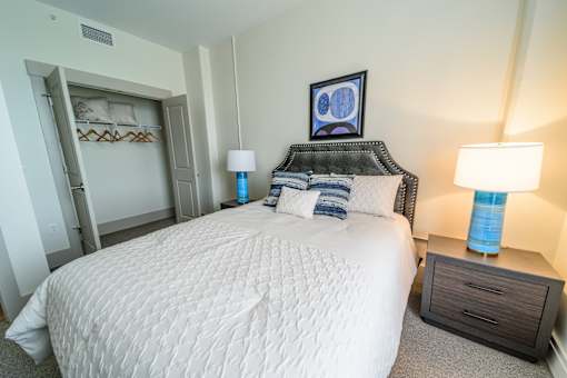 A bedroom with a large bed and two lamps.