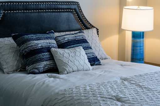 A bed with a white comforter and blue and white pillows.