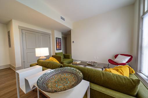 A living room with a green couch and a yellow throw pillow.