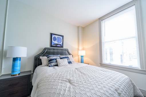 A bedroom with a large bed and two blue lamps.