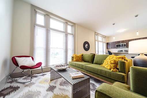 A living room with a green couch, a red chair, and a patterned rug.