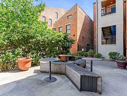 A patio with a table and chairs surrounded by potted plants.