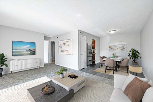 A modern living room with a white sofa, a coffee table, and a painting on the wall.