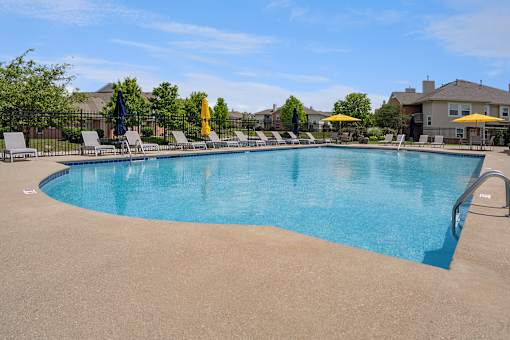 A large swimming pool surrounded by lounge chairs and umbrellas.