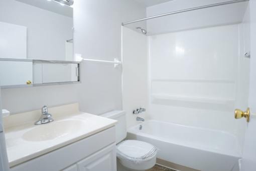 A white bathroom with a sink, toilet and bathtub.