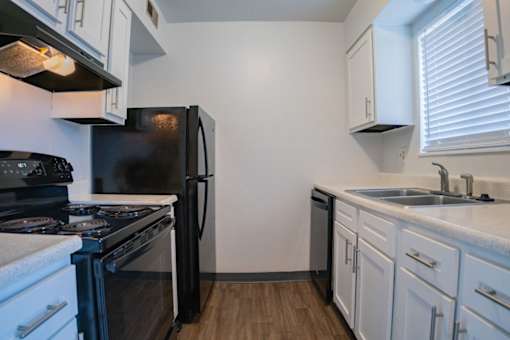 A kitchen with black appliances and white cabinets.