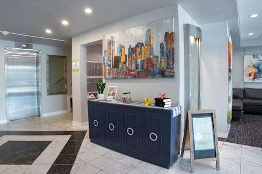 A reception area with a blue cabinet and a large cityscape painting on the wall.