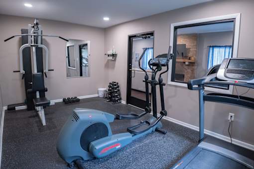 A home gym with a treadmill, elliptical trainer, and a stationary bike.