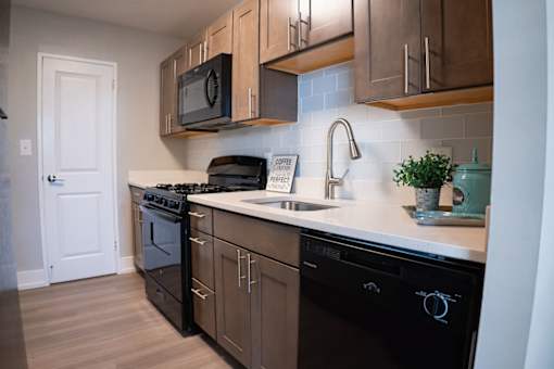 A kitchen with black appliances and wooden cabinets.