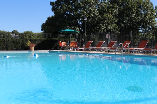a large swimming pool with lounge chairs and umbrellas