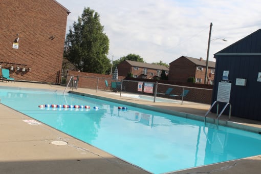 a swimming pool with a brick building and a fence around it