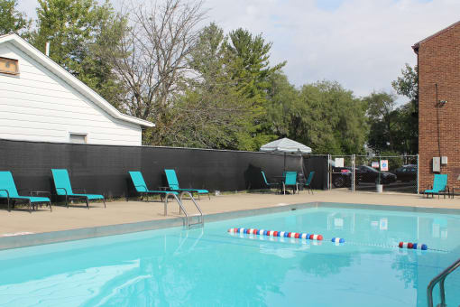 a swimming pool with chairs and a fence around it