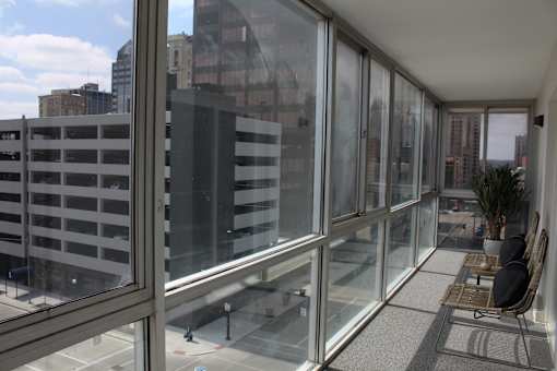 A balcony with glass doors overlooks a parking garage and buildings.