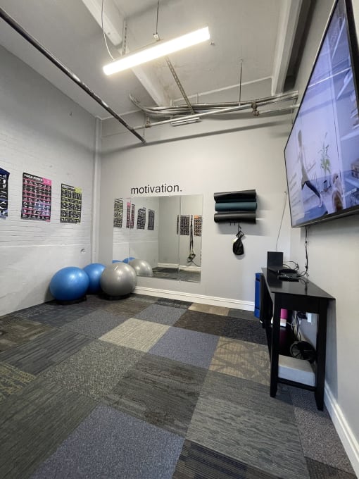 a room with a large screen on the wall and a bunch of exercise balls on the floor