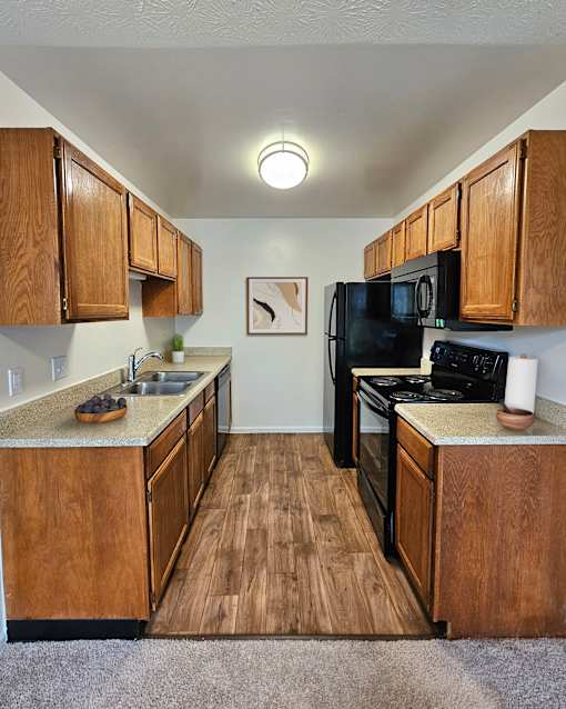A kitchen with wooden cabinets and black appliances.