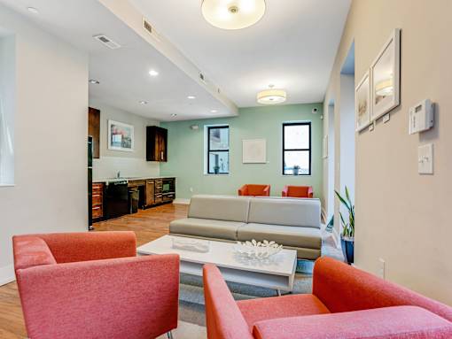 A living room with a grey couch and red chairs.