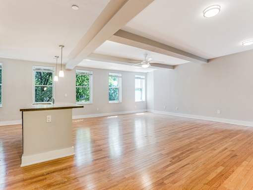 A large empty room with wooden floors and a ceiling fan.