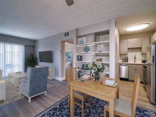 A dining room with a table set for two and a kitchen area in the background.