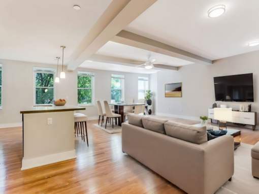 A modern living room with a kitchen in the background.