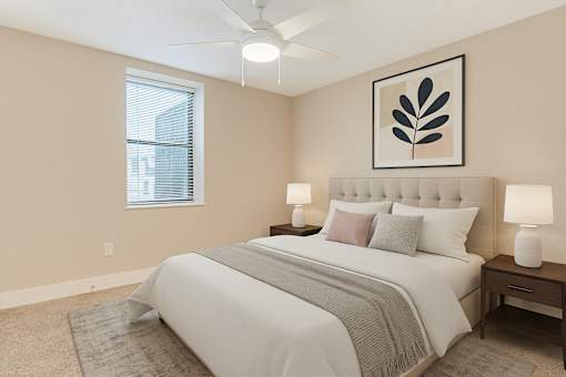 A bedroom with a large bed, two lamps, and a framed picture on the wall.