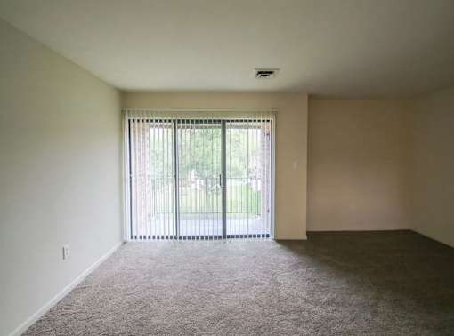 A room with a carpeted floor and a sliding glass door.