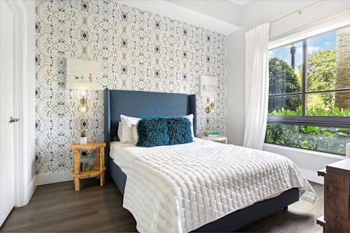 A bedroom with a large bed and a window overlooking a garden.