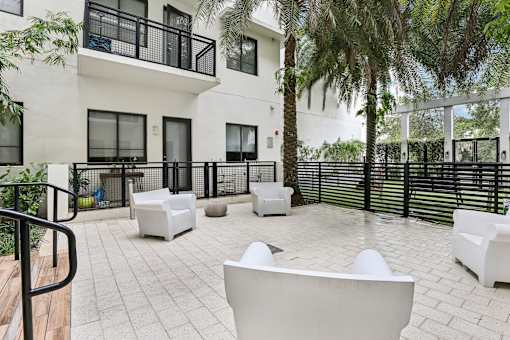 A patio with white furniture and a black railing.