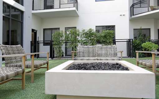 A modern outdoor seating area with a fire pit in the center.