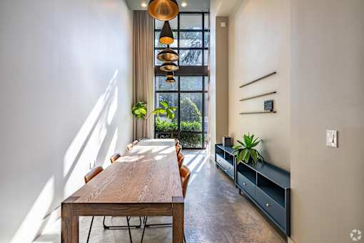 A long wooden table with chairs is in a room with a window.