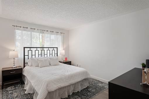A bedroom with a bed, nightstands, and a window.