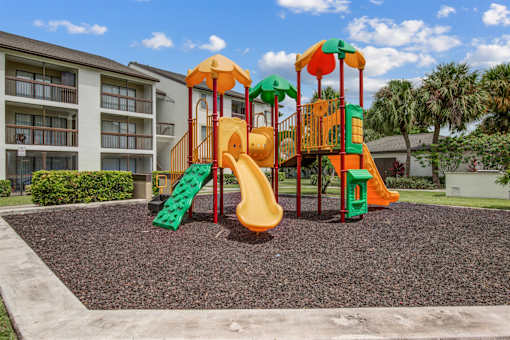 A playground with a yellow slide and a green slide.