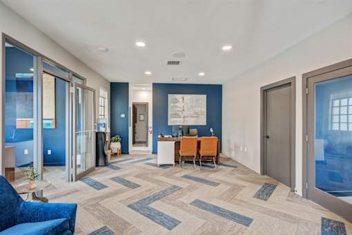 A hallway with a blue couch and a table with chairs.