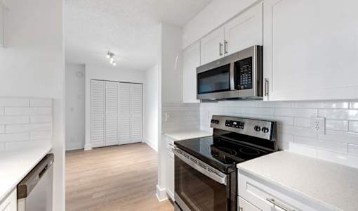A kitchen with a black stove top oven and white cabinets.