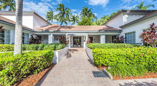 A white house with a red roof and a brick pathway leading to the front door.