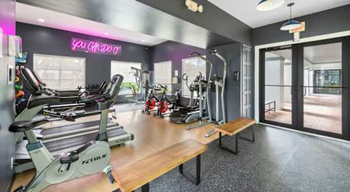 A gym with a variety of equipment including treadmills, weights, and exercise machines.