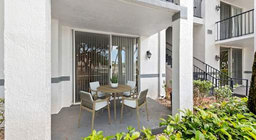 A patio with a table and chairs is surrounded by white columns.