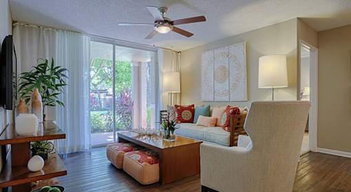 A living room with a couch, a chair, a table, and a ceiling fan.