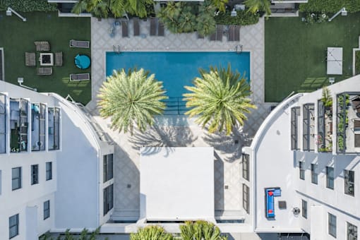 A white building with a pool and palm trees.