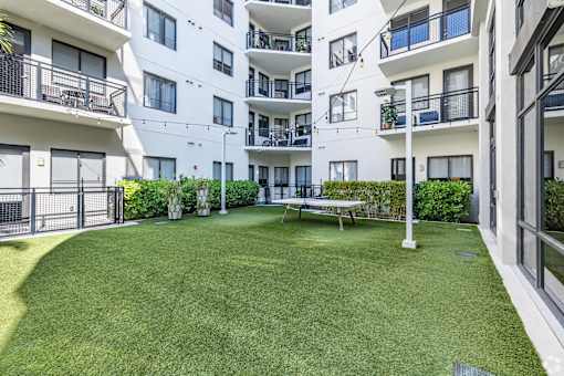 A grassy courtyard surrounded by white apartment buildings.